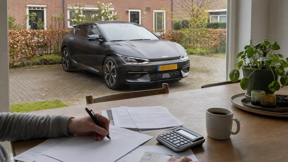 Papieren, rekenmachine en koffie op een keukentafel, met een elektrische auto op de oprit buiten