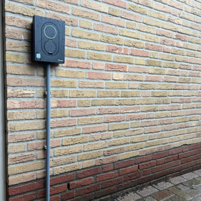 Zaptec Go laadpaal aan een gele bakstenen gevel met netjes weggewerkte kabelbuis