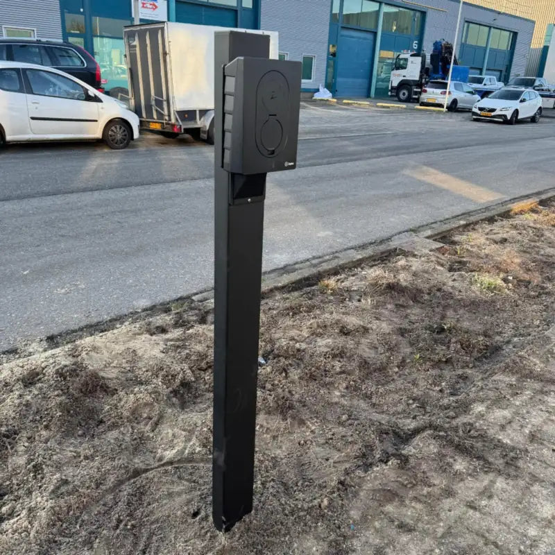 Zwarte Zaptec Go laadpaal op een vrijstaande paalbevestiging, geplaatst langs de straat van een bedrijventerrein.